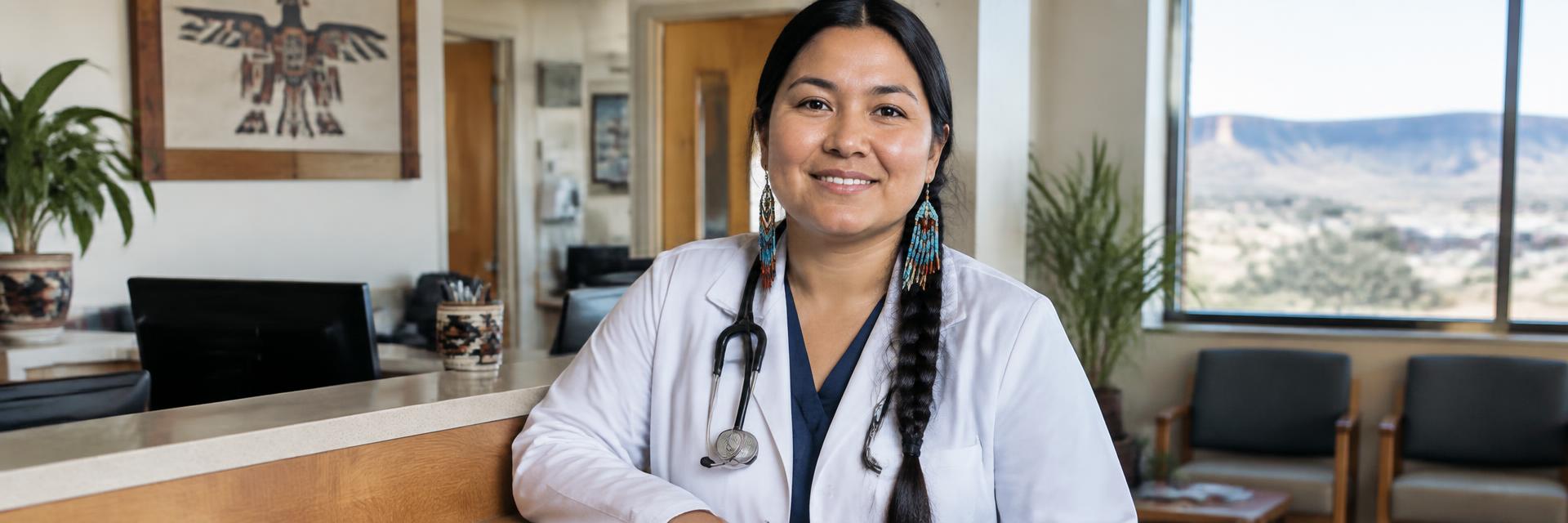 A Native American woman in a white coat smiling at a community clinic front desk