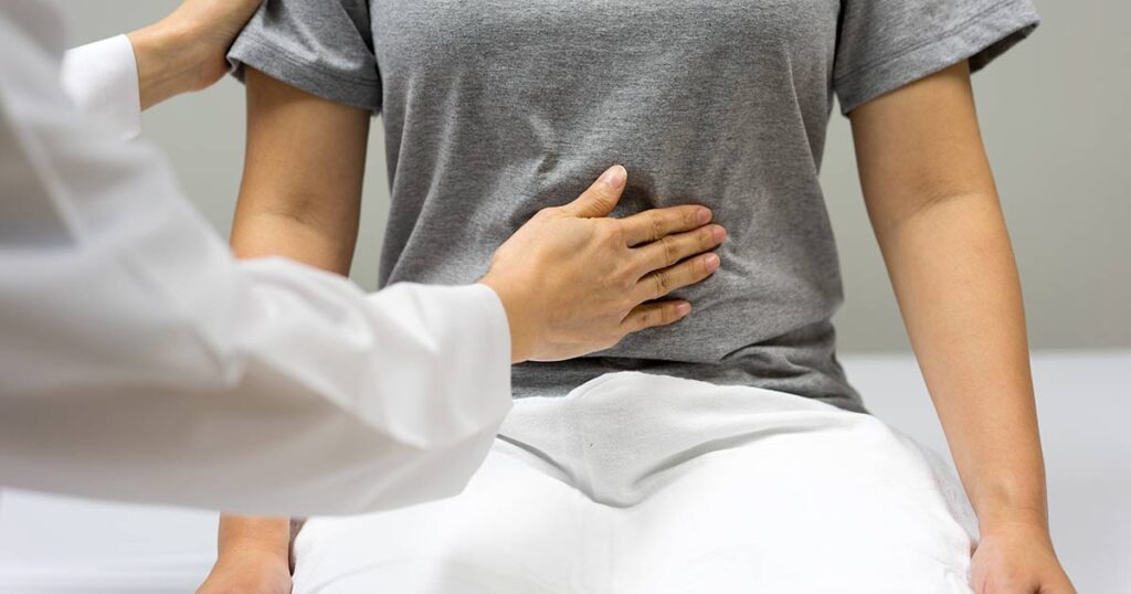 Nurse checking a patient's level of pain in their stomach